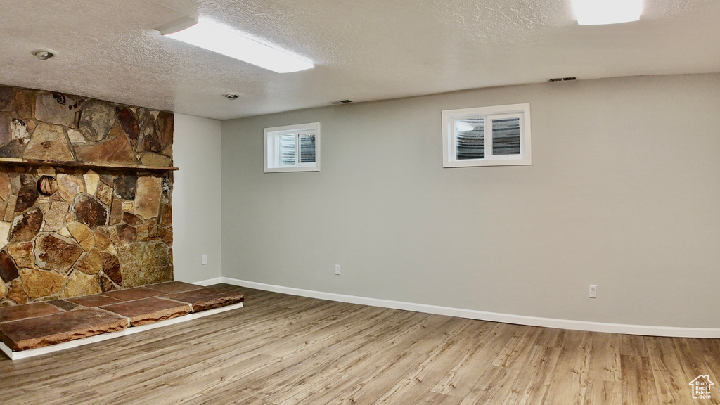 Basement with baseboards, a textured ceiling, and wood finished floors