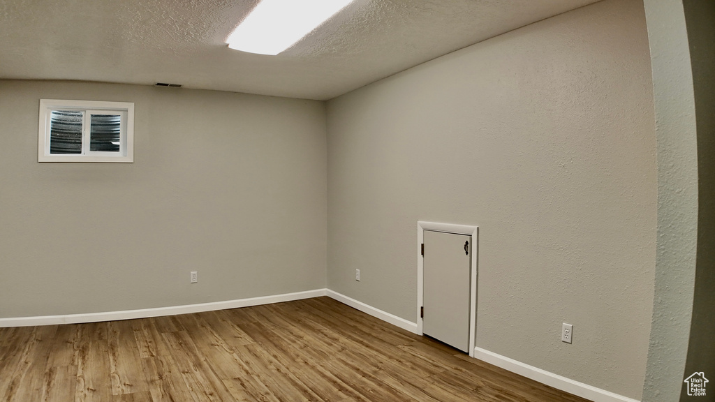 Unfurnished room featuring baseboards, a textured ceiling, and wood finished floors