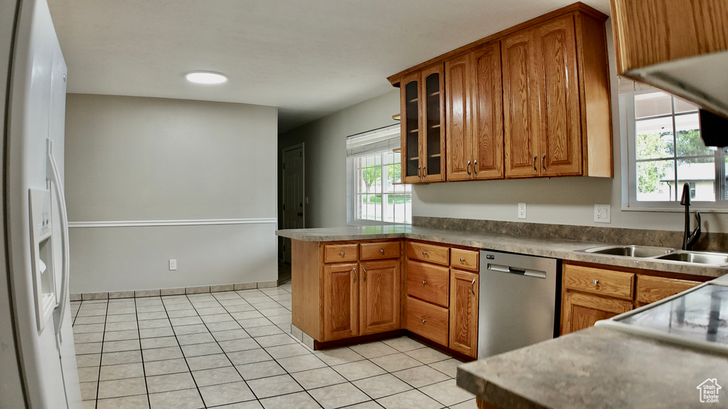 Kitchen featuring a sink, brown cabinetry, white fridge with ice dispenser, a peninsula, and stainless steel dishwasher