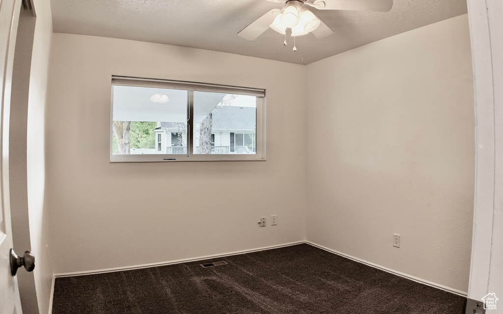 Unfurnished room with dark colored carpet, a ceiling fan, baseboards, and visible vents
