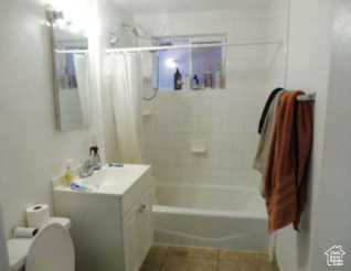 Full bathroom with vanity, tile patterned flooring, shower / bath combo with shower curtain, and toilet