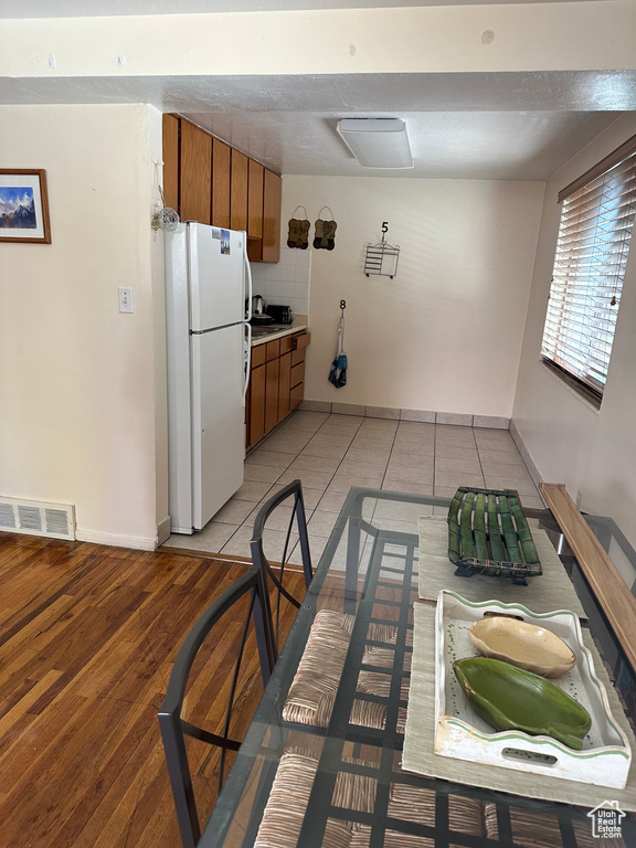 Kitchen with visible vents, freestanding refrigerator, baseboards, brown cabinets, and light tile patterned floors