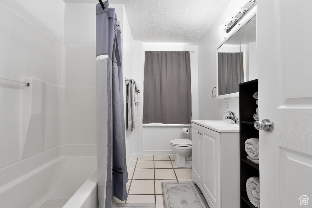 Full bathroom with tile patterned flooring, vanity, toilet, a textured ceiling, and shower / bath combination with curtain