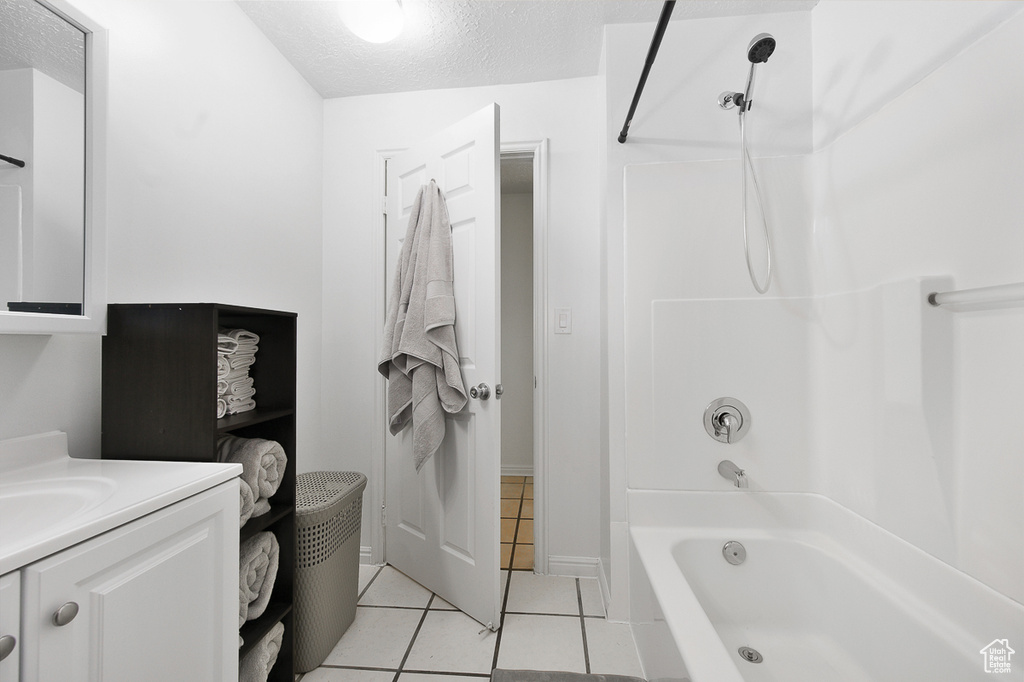 Bathroom featuring tile patterned floors, vanity, shower / tub combination, and a textured ceiling