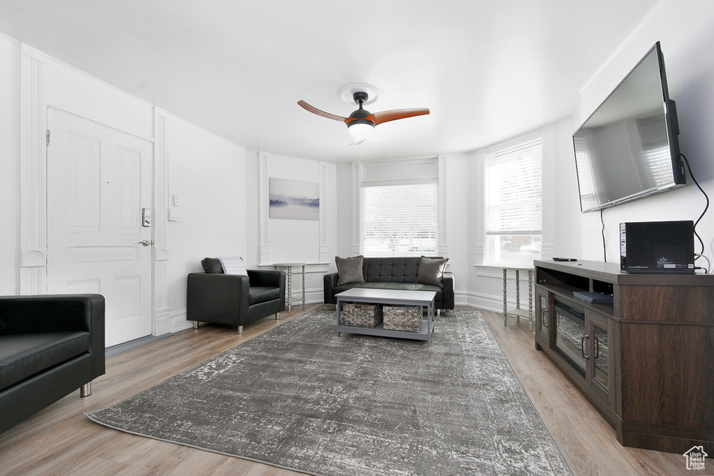 Living area featuring a ceiling fan, baseboards, and light wood-style flooring