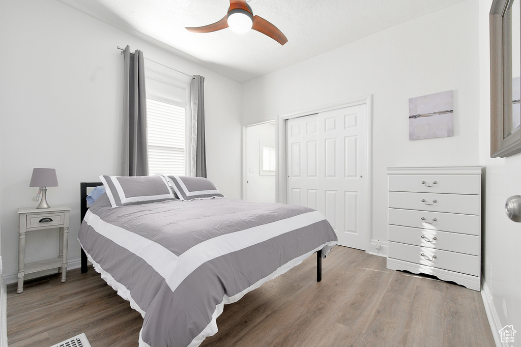 Bedroom with baseboards, ceiling fan, a closet, and light wood-type flooring