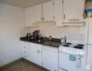Kitchen with decorative backsplash, a sink, under cabinet range hood, white appliances, and white cabinetry