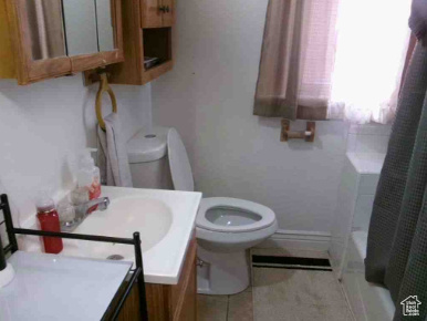 Full bath featuring vanity, shower / bath combo with shower curtain, toilet, baseboards, and tile patterned floors