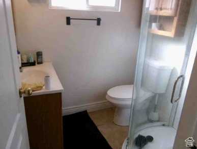 Full bathroom with a shower stall, vanity, tile patterned floors, baseboards, and toilet