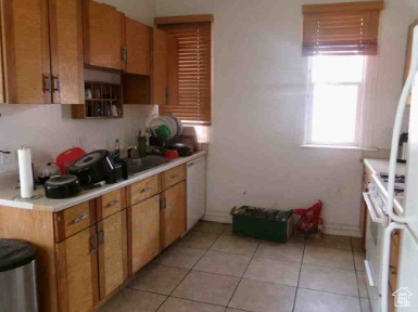 Kitchen with baseboards, light countertops, light tile patterned flooring, and brown cabinets