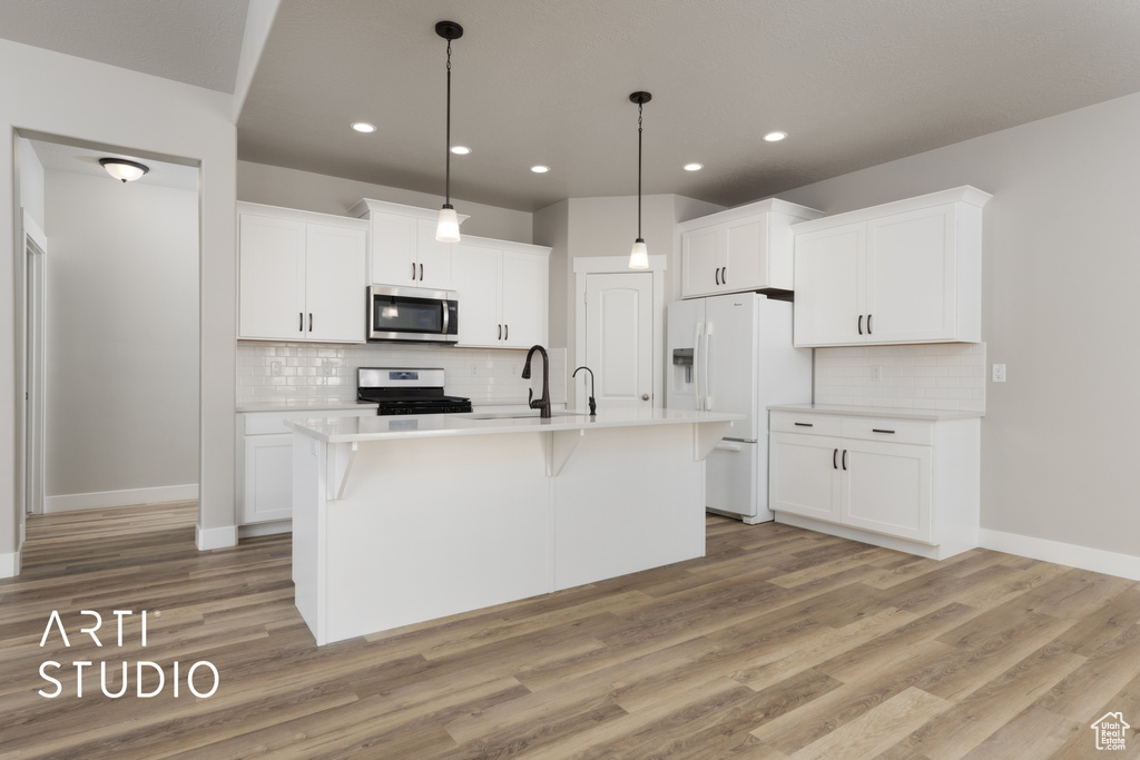 Kitchen featuring light wood-style flooring, a sink, stainless steel appliances, a kitchen breakfast bar, and tasteful backsplash