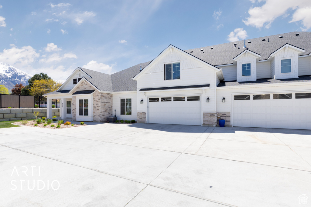 View of front of property with driveway, board and batten siding, fence, a garage, and stone siding