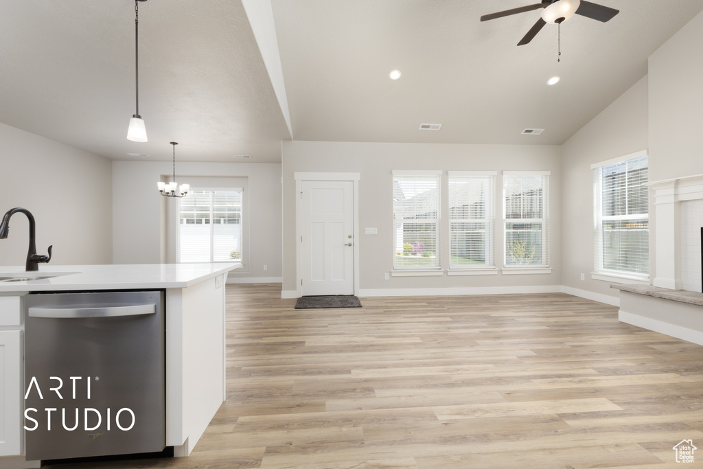 Kitchen with dishwasher, a sink, ceiling fan with notable chandelier, open floor plan, and light countertops