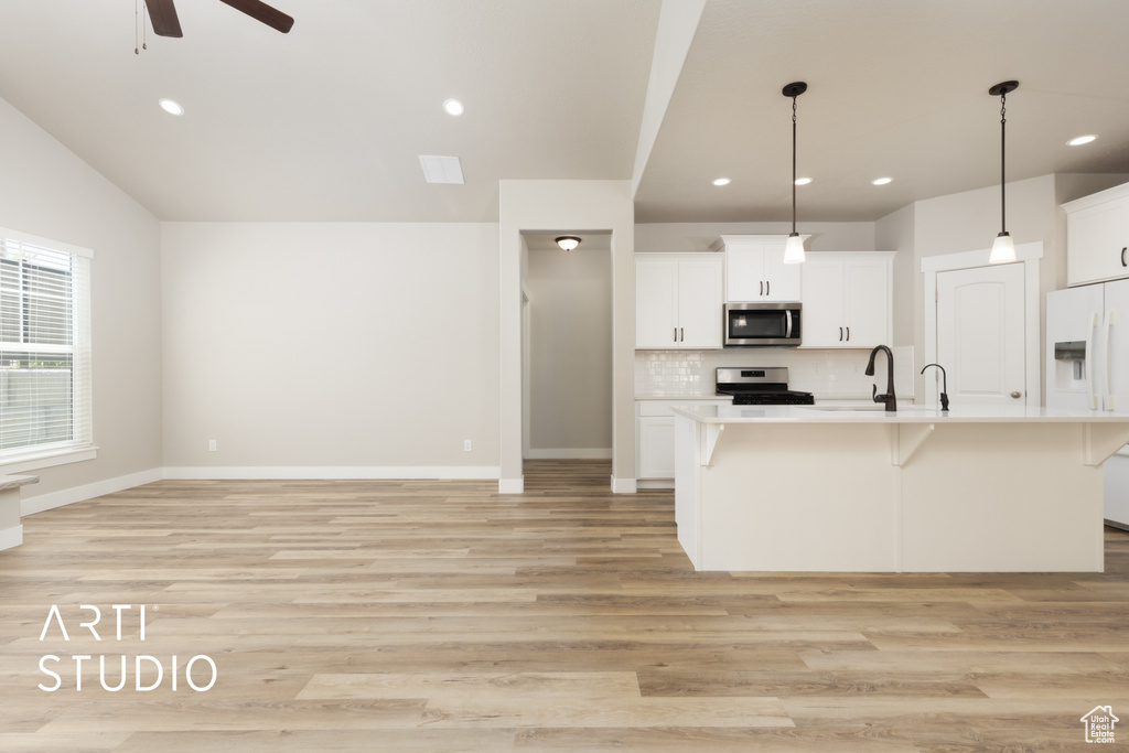 Kitchen featuring a breakfast bar, ceiling fan, light wood-style flooring, light countertops, and appliances with stainless steel finishes