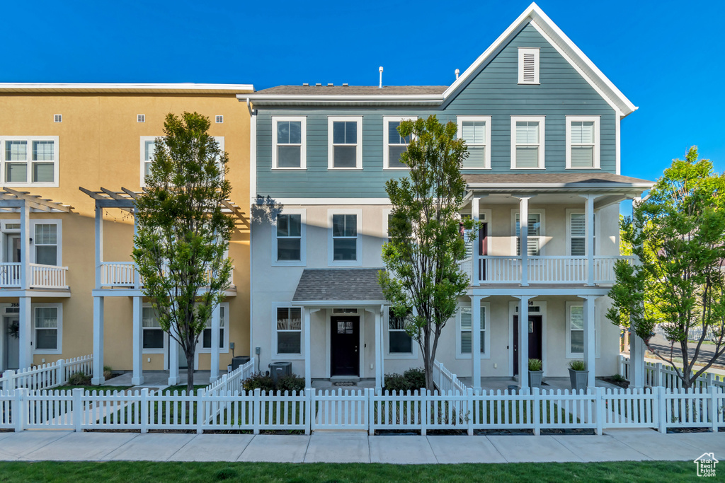 View of front of property with a balcony, a pergola, stucco siding, and a fenced front yard