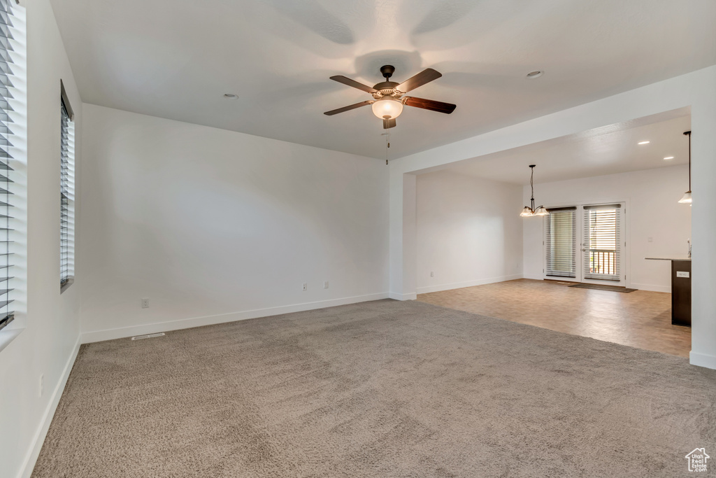 Spare room with carpet flooring, baseboards, ceiling fan with notable chandelier, and recessed lighting