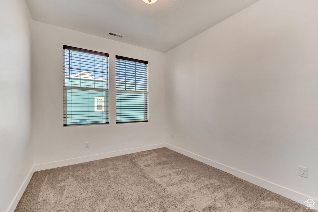 Carpeted empty room featuring baseboards and visible vents