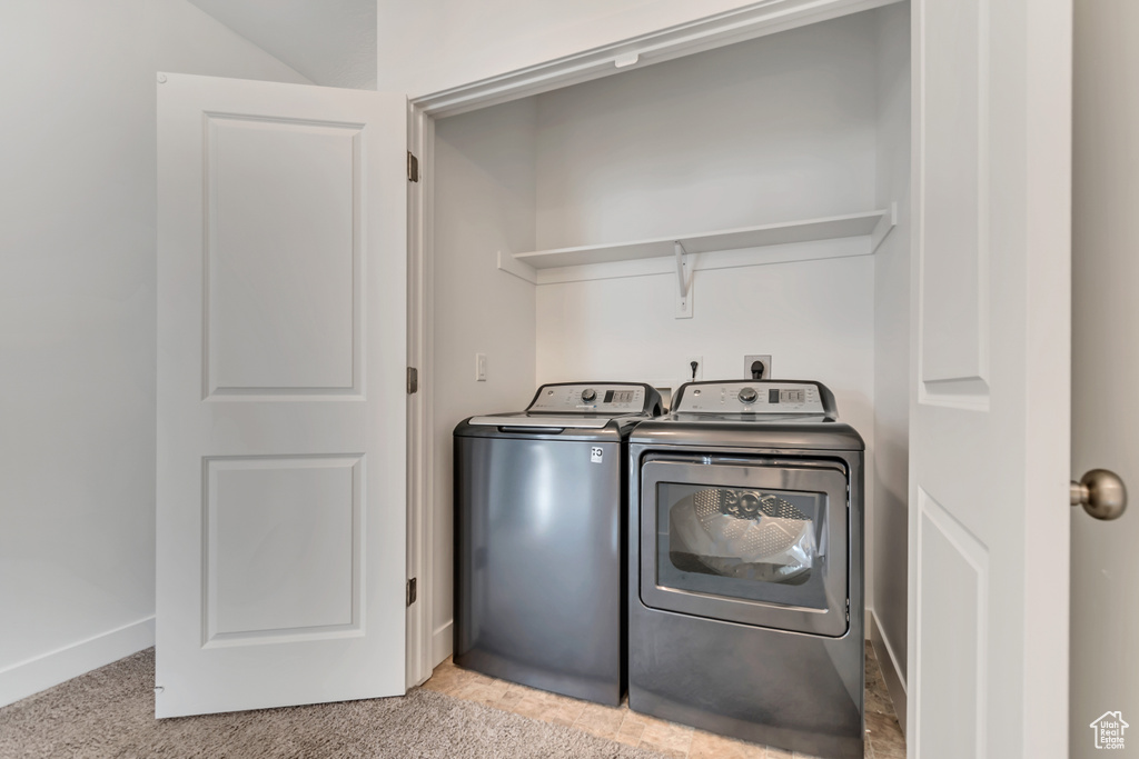 Clothes washing area with baseboards, washing machine and dryer, laundry area, and light colored carpet