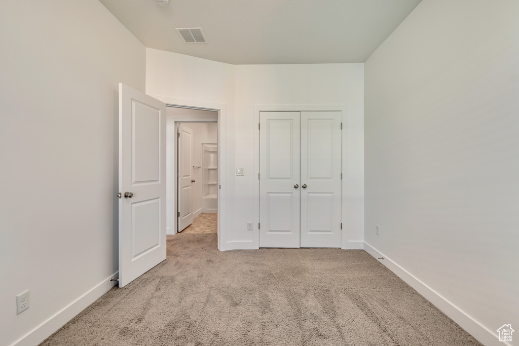 Unfurnished bedroom featuring carpet flooring, baseboards, a closet, and visible vents