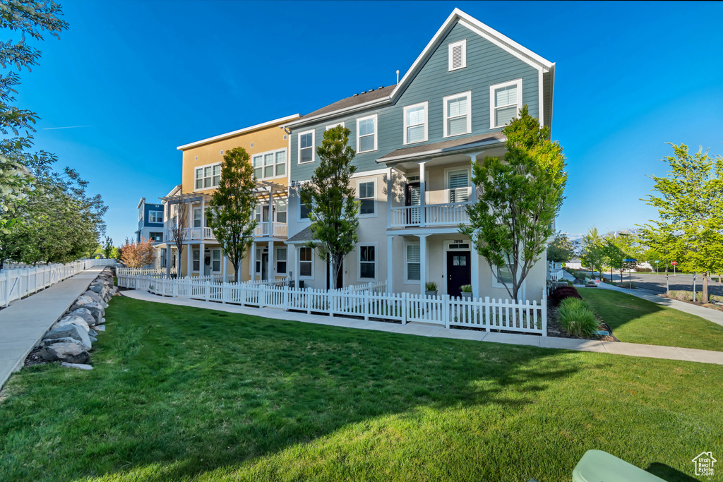 View of property with a fenced front yard, a balcony, and a front yard