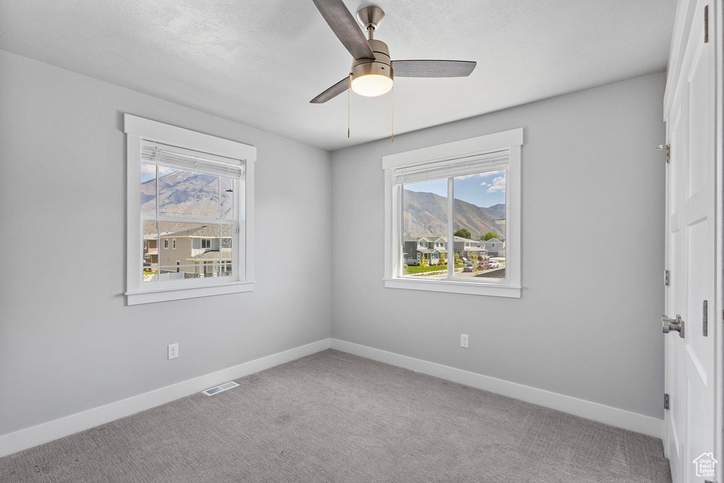 Unfurnished room featuring baseboards, carpet flooring, visible vents, and a ceiling fan