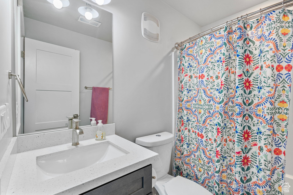 Full bath featuring toilet, visible vents, vanity, and a shower with curtain