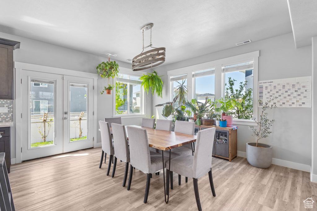 Dining space with baseboards, visible vents, french doors, and light wood-style flooring