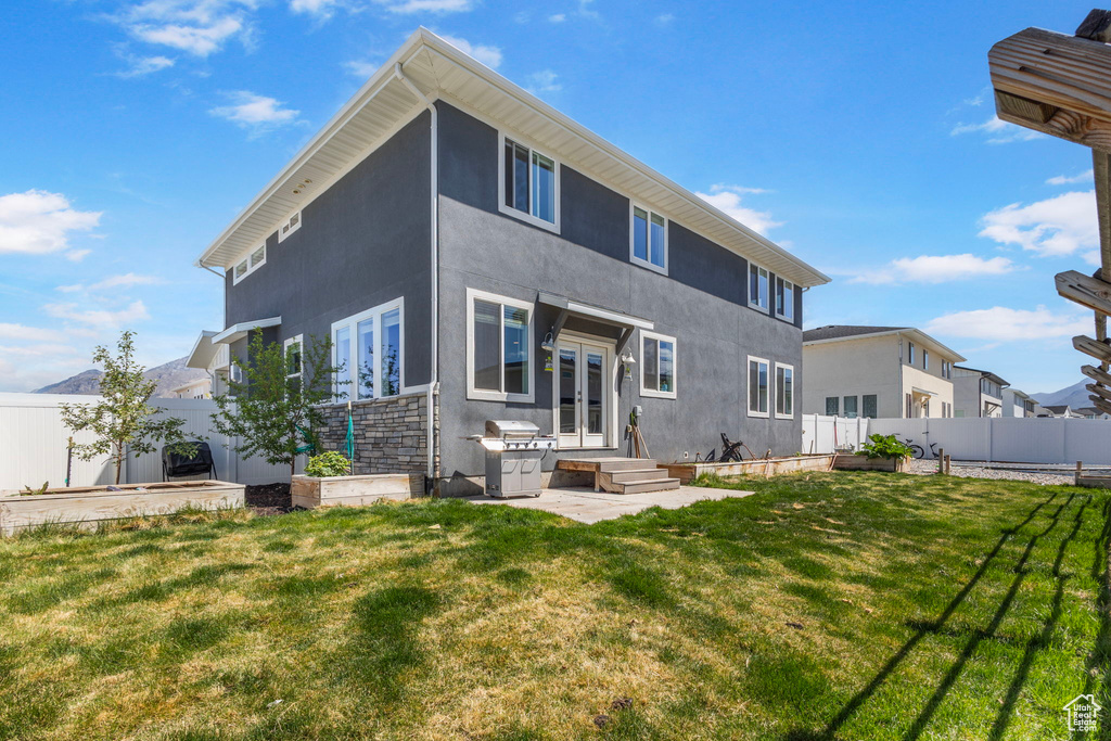 Back of property featuring a yard, fence, stucco siding, and french doors