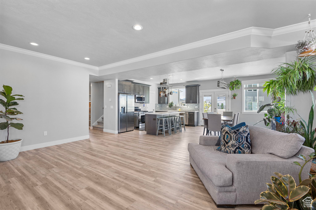 Living area featuring crown molding, light wood-style floors, baseboards, and recessed lighting