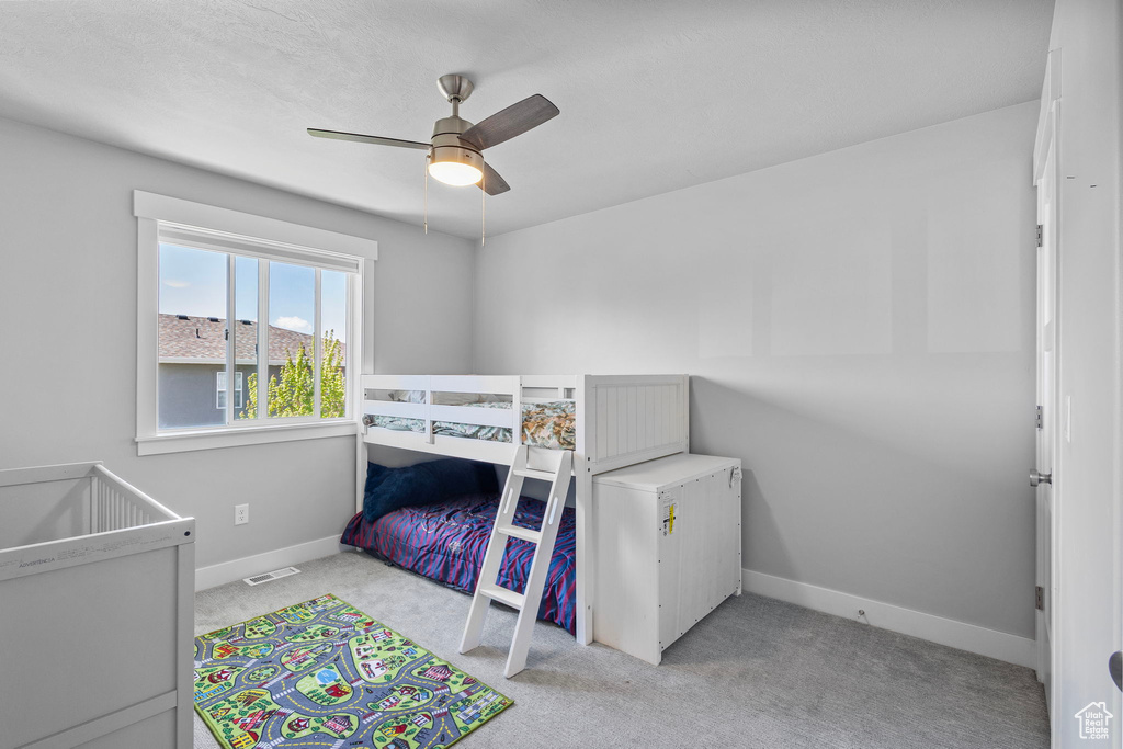 Carpeted bedroom with ceiling fan, baseboards, and visible vents