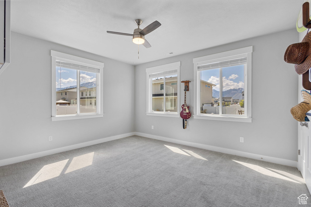 Carpeted empty room with visible vents, baseboards, and a ceiling fan