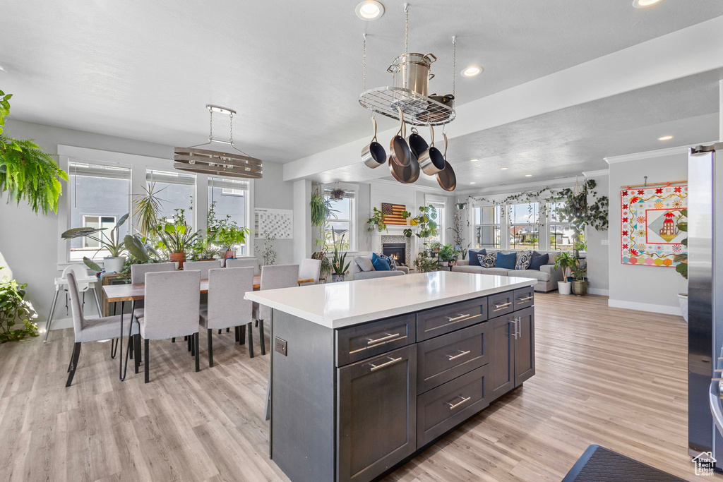 Kitchen with a warm lit fireplace, recessed lighting, baseboards, light wood finished floors, and light countertops