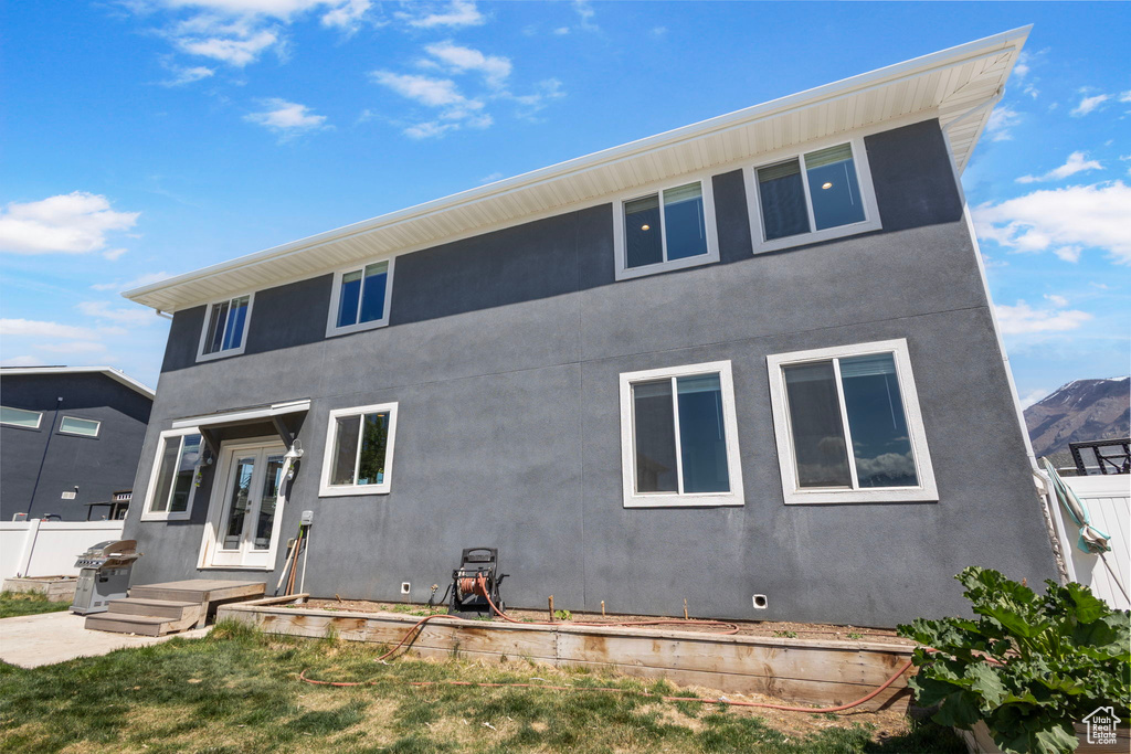 Rear view of house with stucco siding, crawl space, and fence