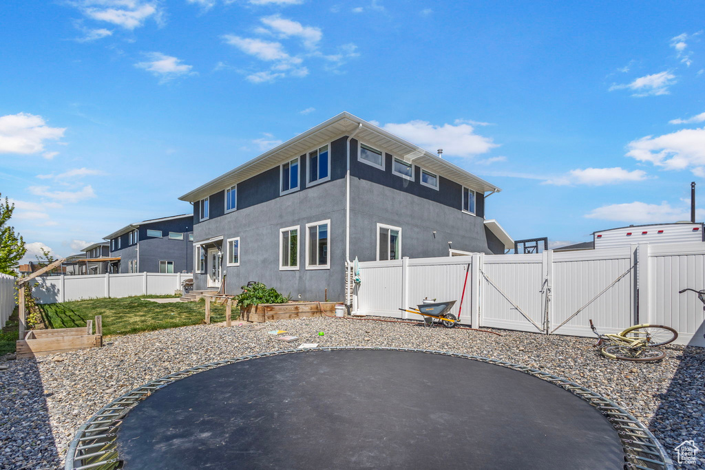 Back of property with a patio, stucco siding, a fenced backyard, and a gate