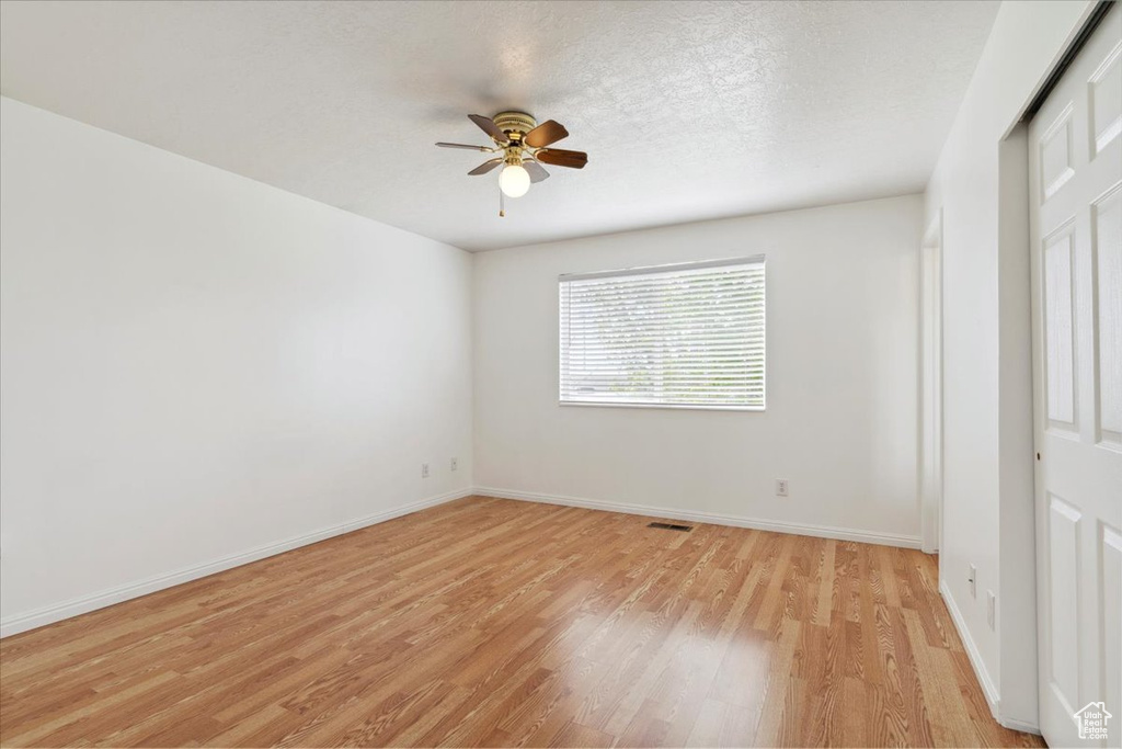 Empty room with a ceiling fan, baseboards, visible vents, and light wood-type flooring