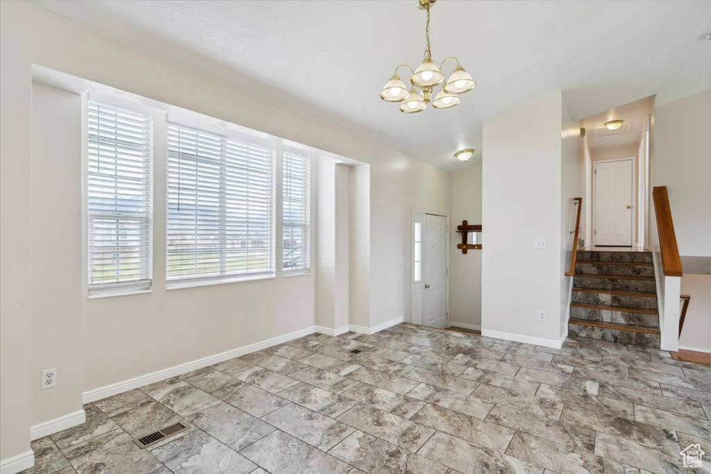 Entrance foyer featuring stone finish floor, baseboards, an inviting chandelier, visible vents, and stairs