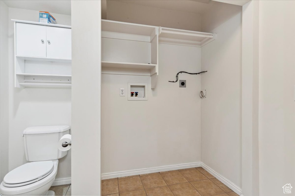 Laundry room featuring laundry area, light tile patterned floors, electric dryer hookup, washer hookup, and baseboards