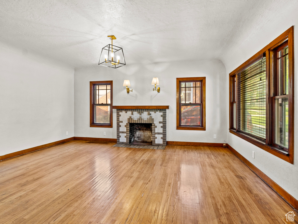 Unfurnished living room with light wood-style flooring, plenty of natural light, baseboards, and a textured ceiling