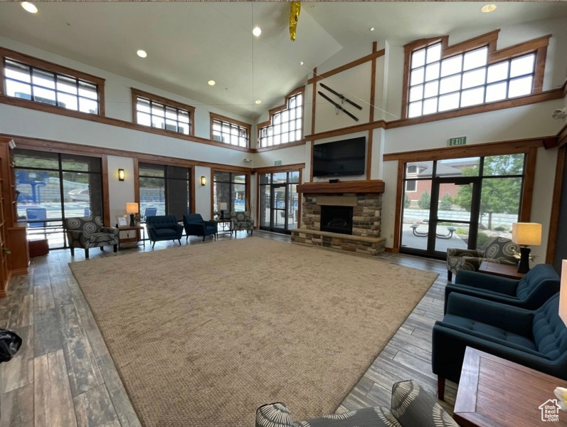 Living room with hardwood / wood-style floors, high vaulted ceiling, recessed lighting, plenty of natural light, and a fireplace