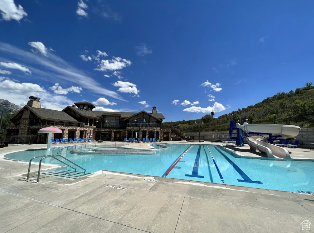 Community pool with a water slide, fence, and a patio