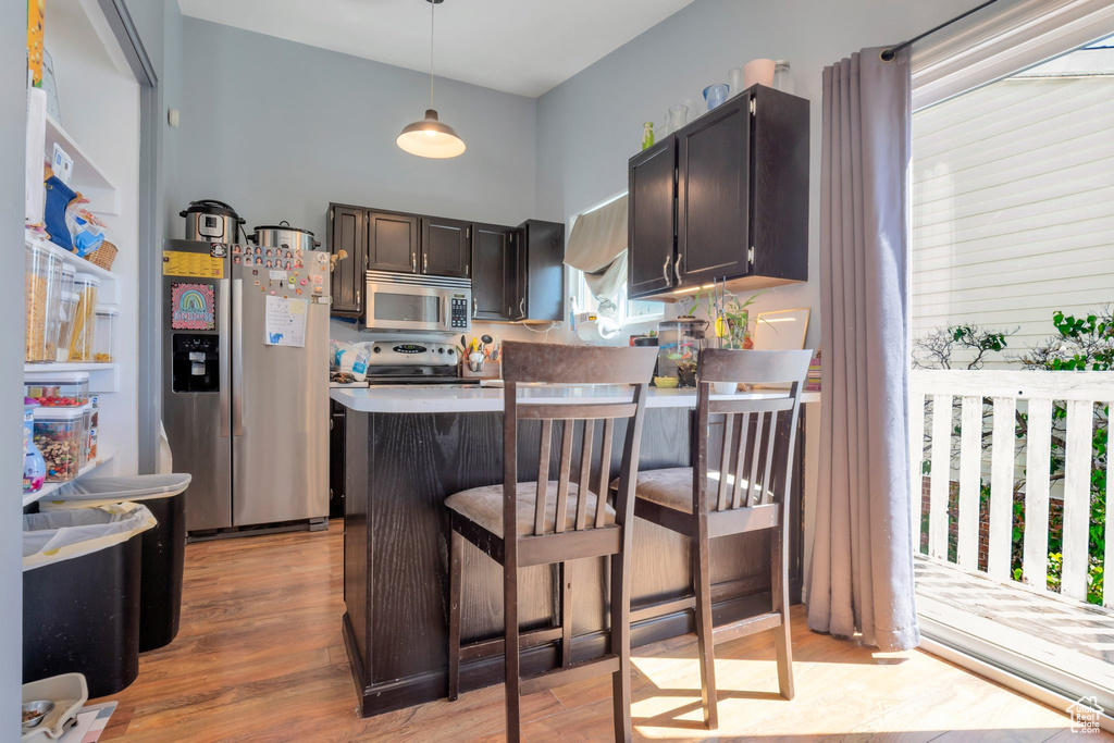Kitchen featuring a peninsula, stainless steel appliances, light wood-style flooring, and pendant lighting