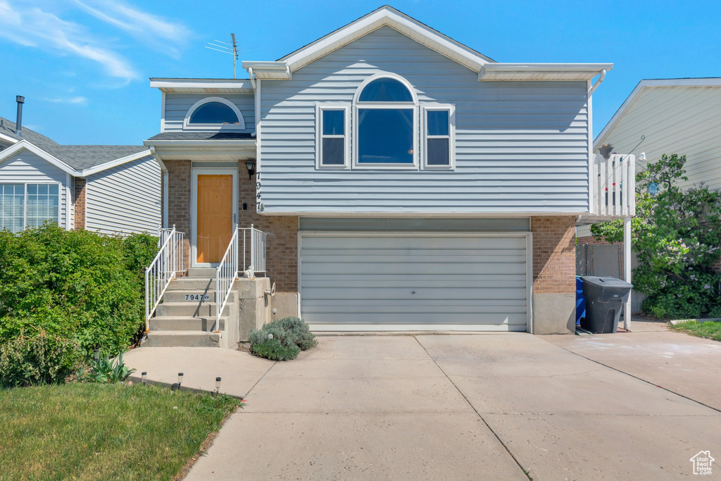 Tri-level home with concrete driveway, brick siding, and a garage