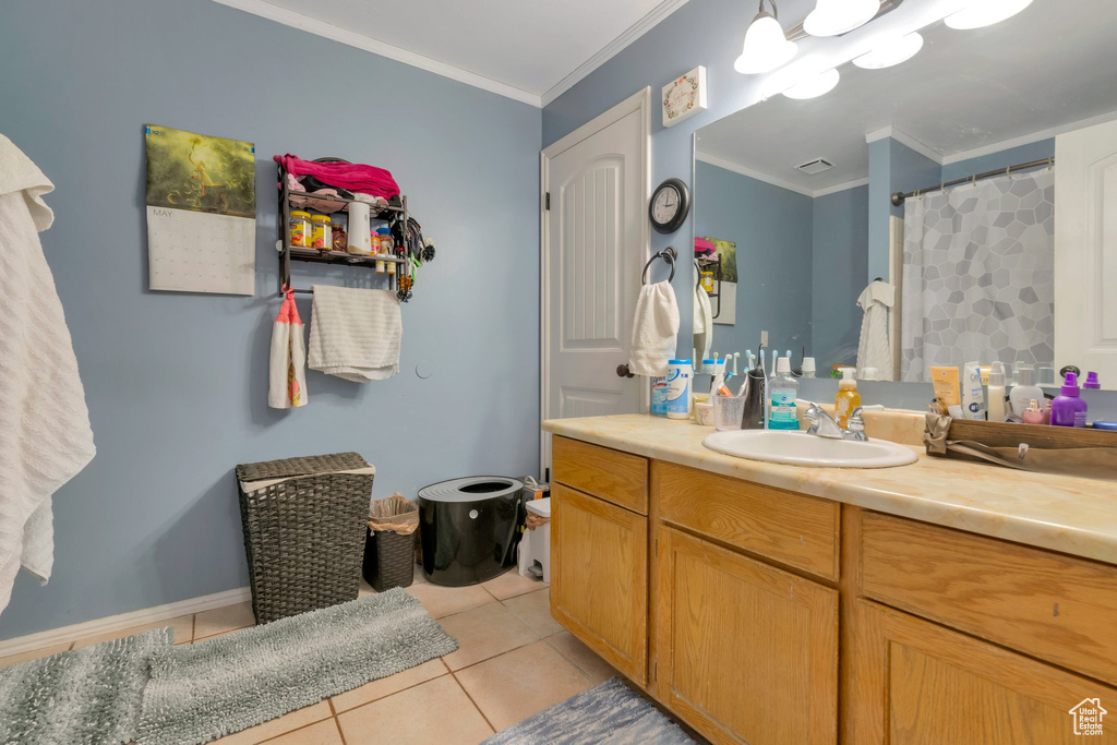 Bathroom featuring tile patterned flooring, crown molding, and vanity