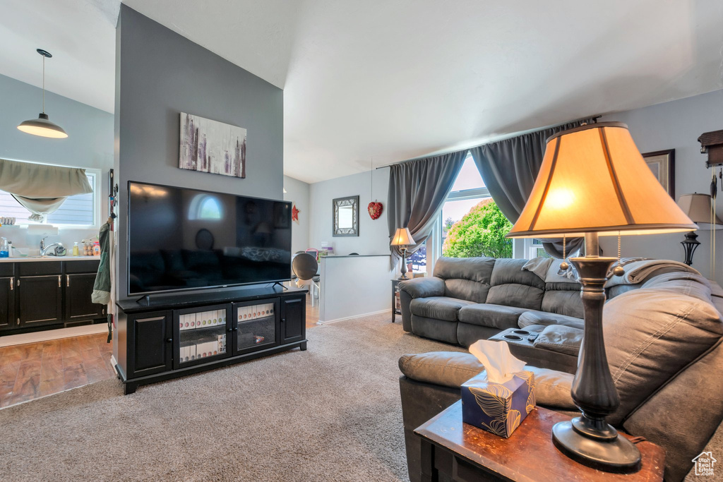 Carpeted living area featuring vaulted ceiling and a sink