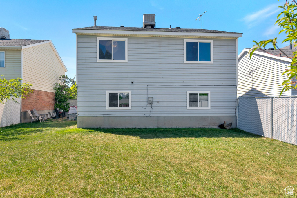 Rear view of property with a yard and fence