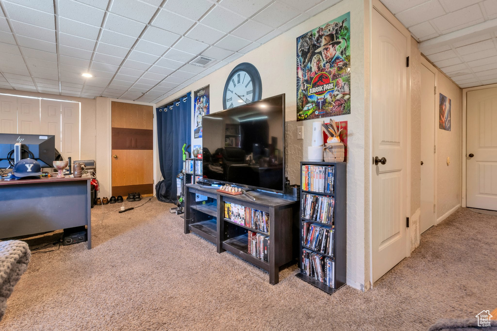 Carpeted living room with a paneled ceiling and visible vents