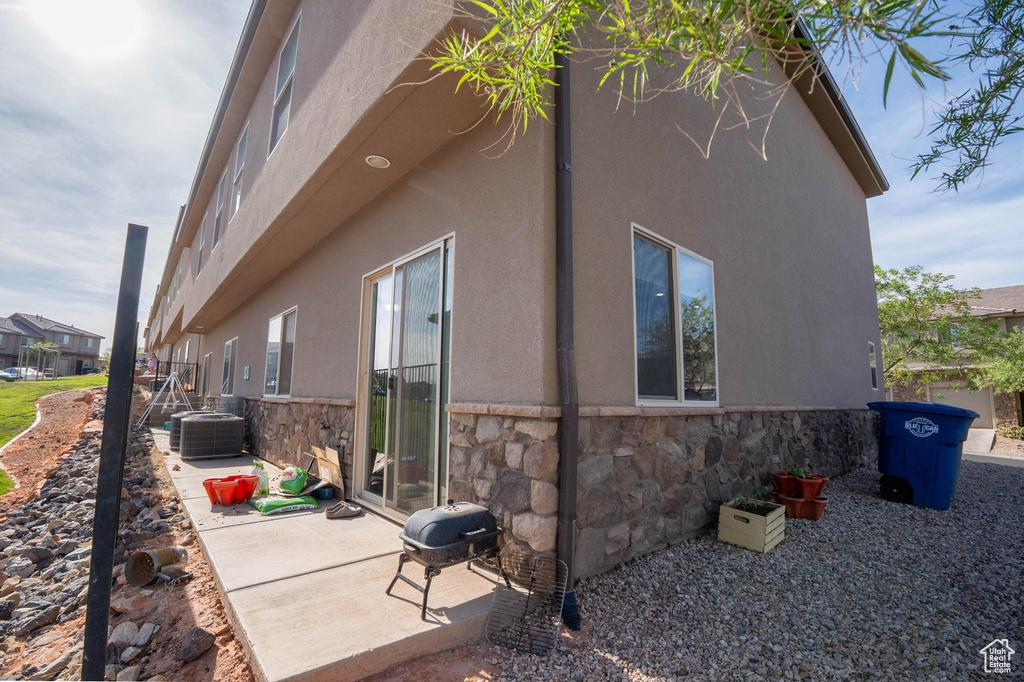 View of property exterior with stone siding, stucco siding, and a patio