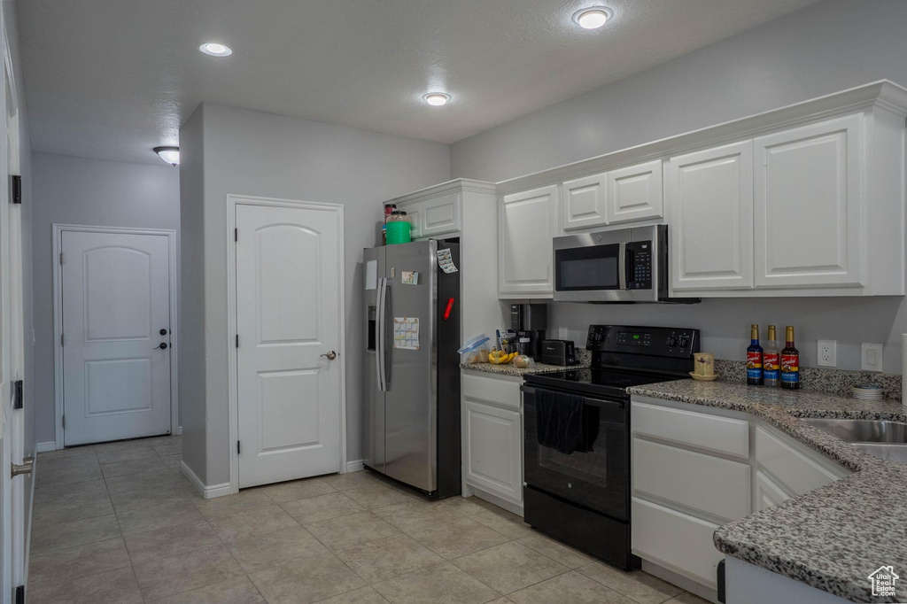 Kitchen with light tile patterned floors, a sink, white cabinetry, appliances with stainless steel finishes, and recessed lighting