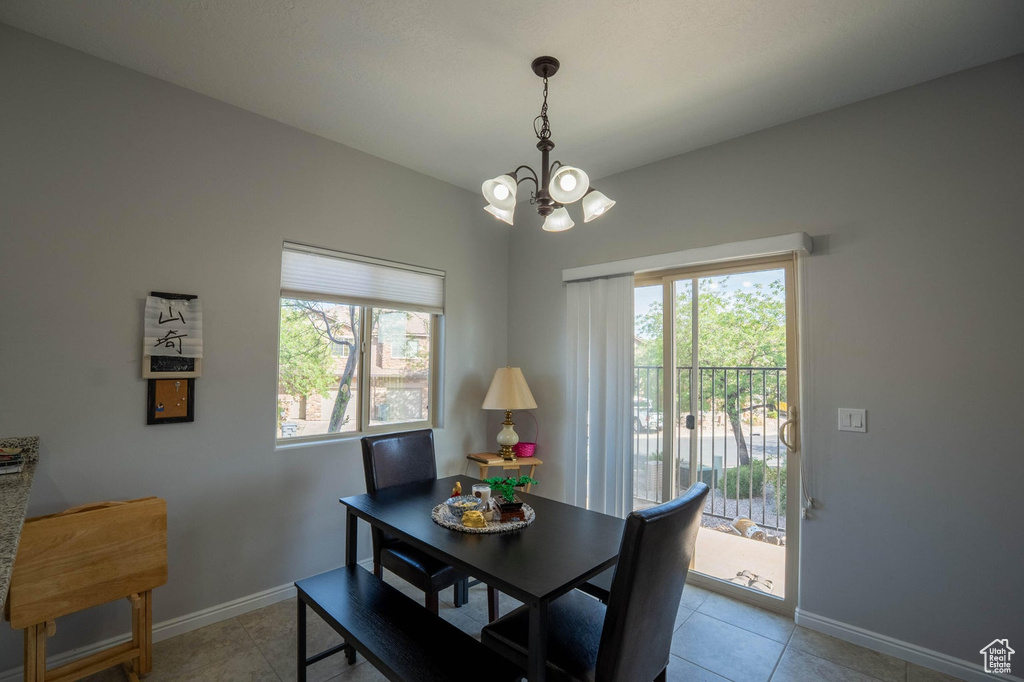 Dining room with an inviting chandelier, light tile patterned flooring, and baseboards