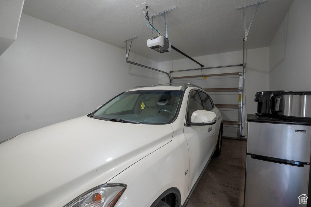 Garage with freestanding refrigerator and a garage door opener